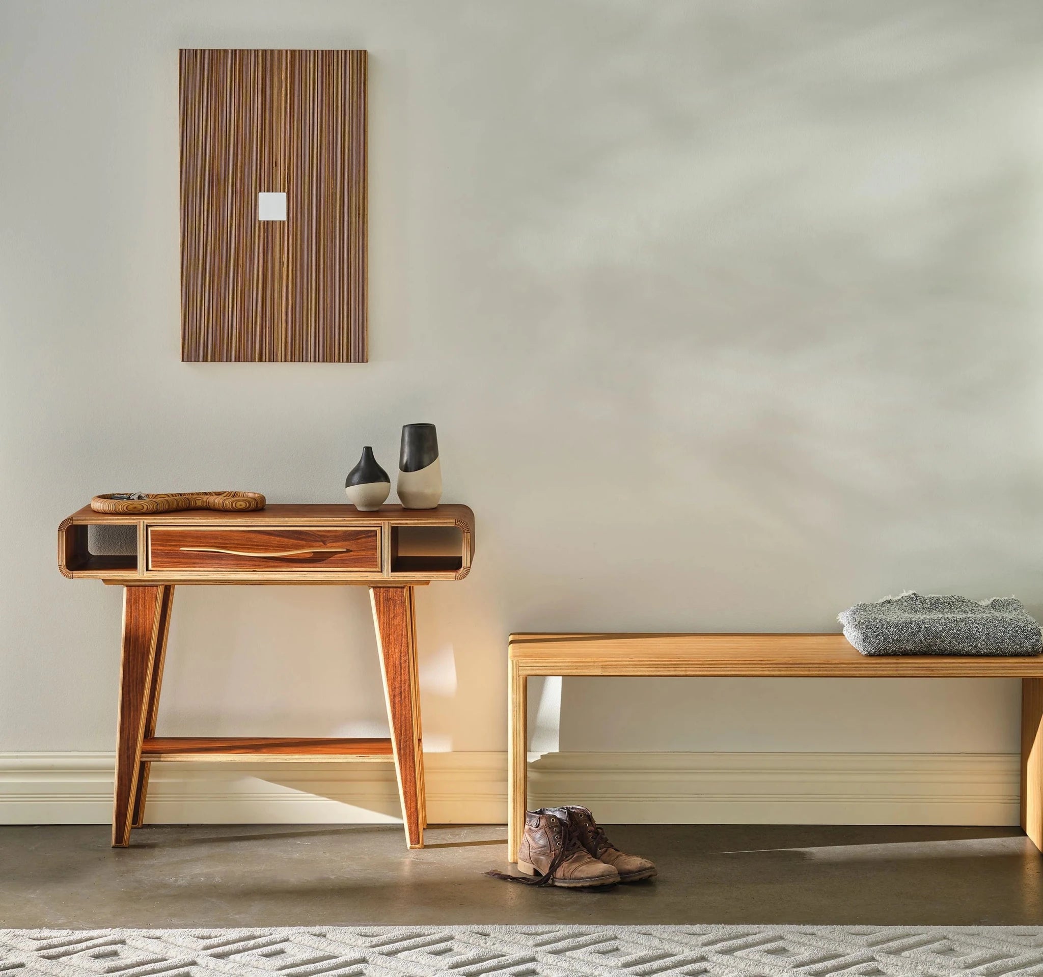 Walnut entry table styled in entryway with vases, beside light bench and boots
