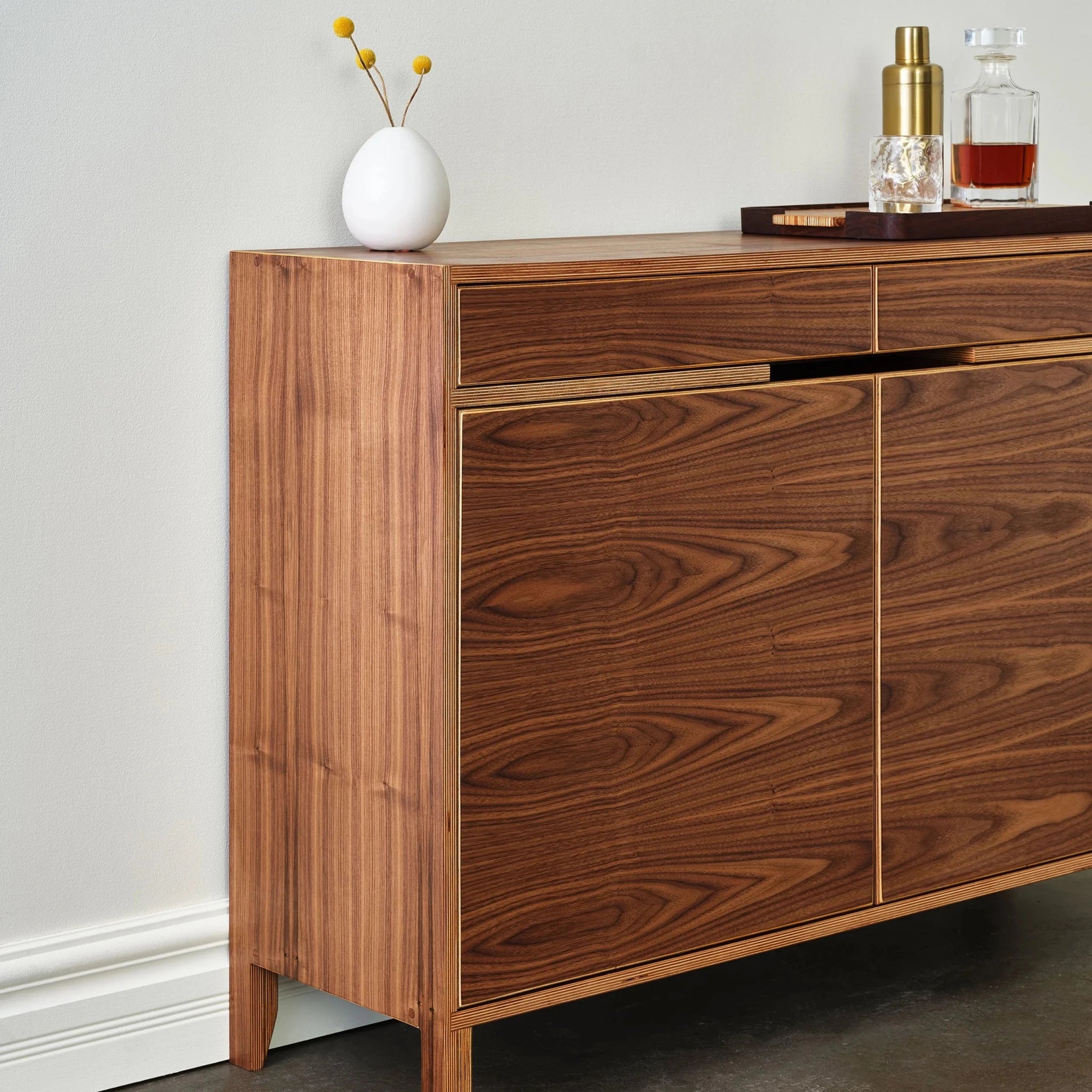 Angled side view of walnut liquor cabinet showing layered birch plywood edges
