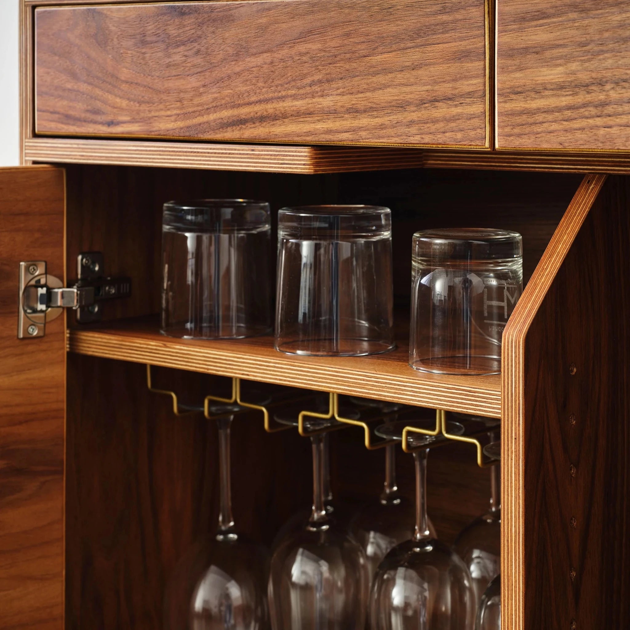 Cabinet interior detail with tumblers on shelf and hanging stemware rack
