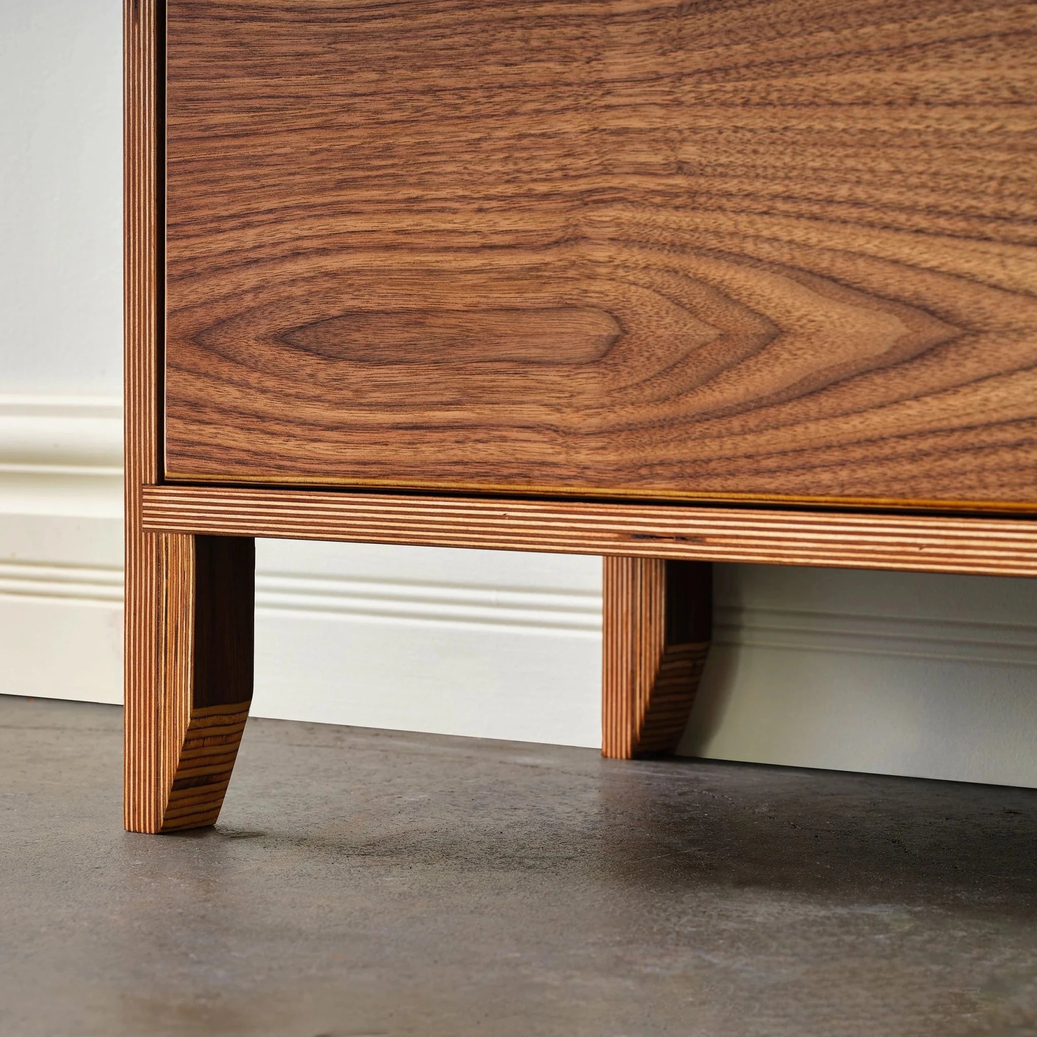 Closeup of tapered layered-birch leg and walnut grain on cabinet base