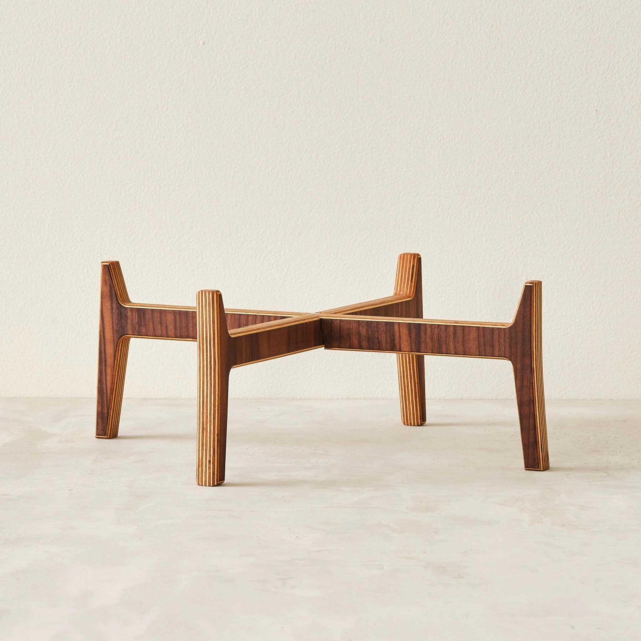 Empty walnut plant stand, four splayed legs showing layered Baltic birch edges, white background
