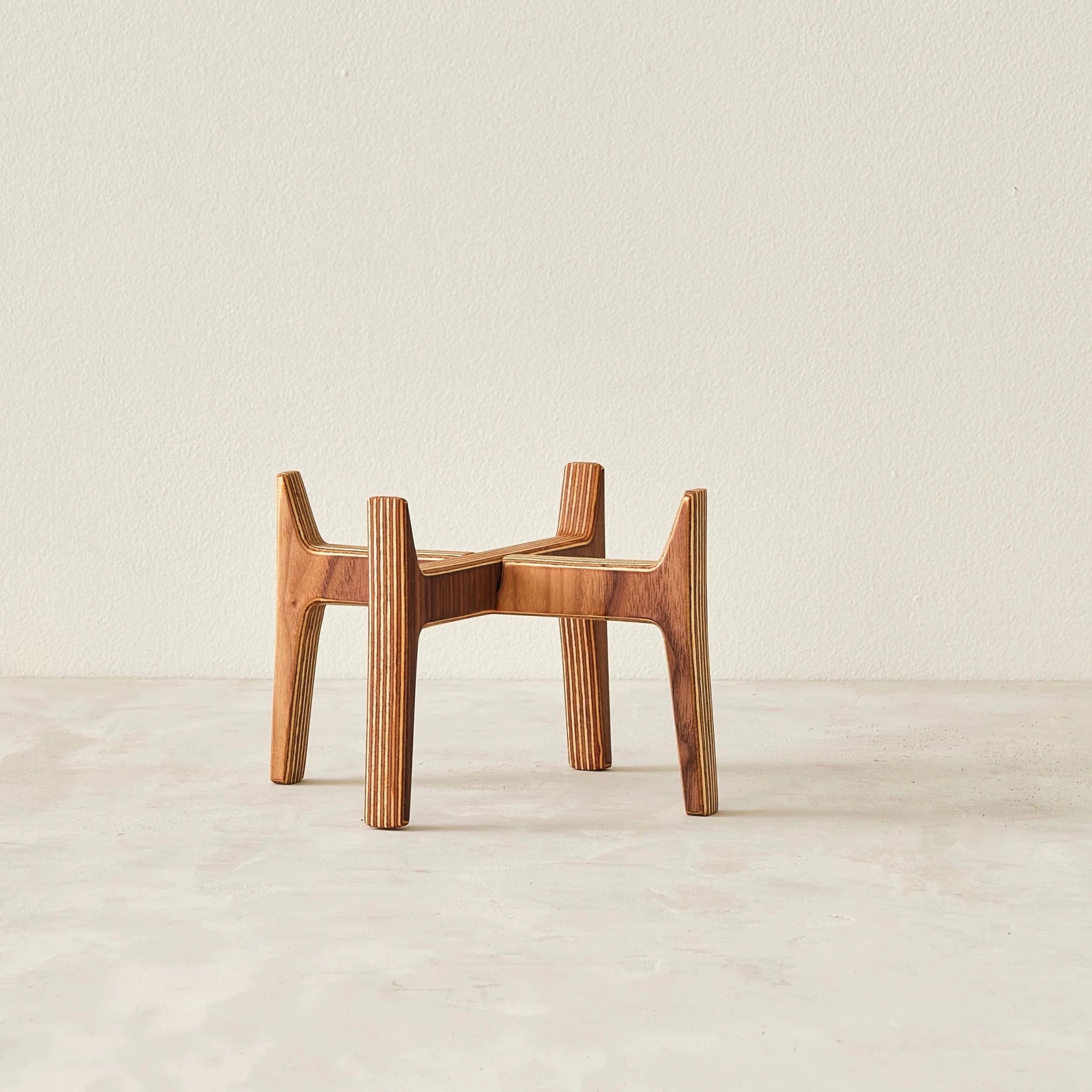 Empty medium walnut and layered birch plywood plant stand, interlocking legs, no pot