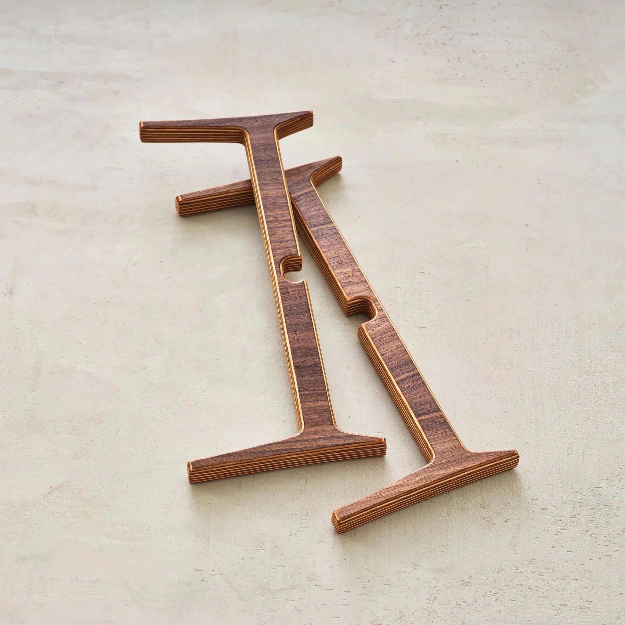 Collapsed plant stand, two flat interlocking walnut pieces showing layered birch plywood edges
