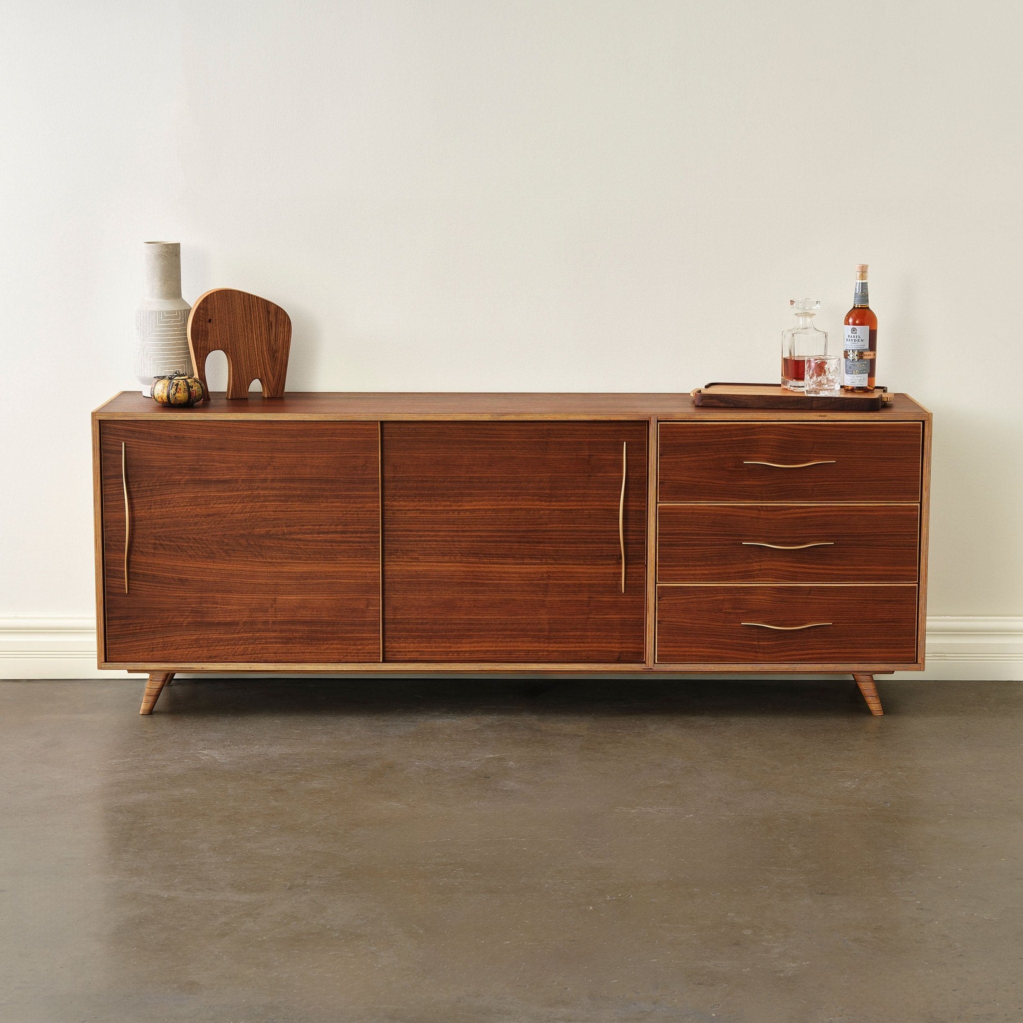 Walnut sideboard staged with vase, wooden elephant and whiskey decanter tray on top