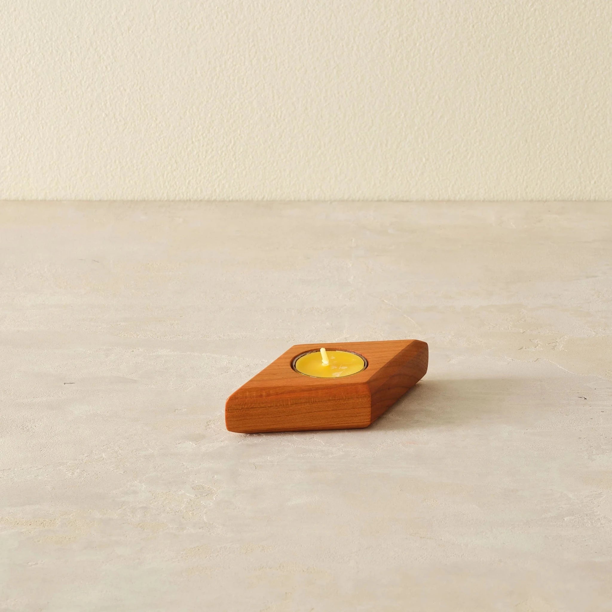 Single cherry diamond-shaped tealight holder, one yellow candle, angled front view