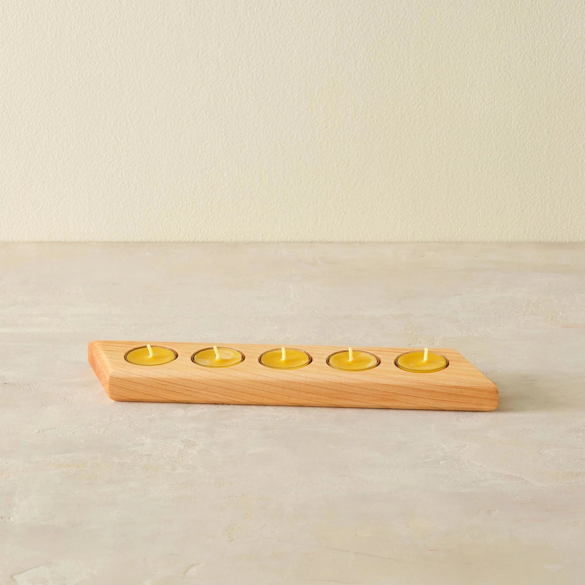 Maple tealight bar with five yellow candles, front view on neutral background